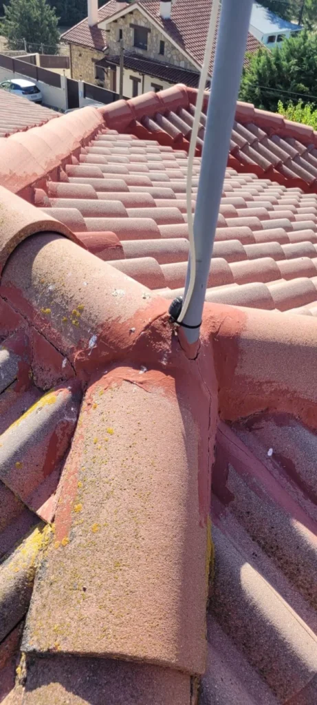 Impermeabilización de remates en tejado de Lozoyuela con sellador rojo en las uniones de tejas y tubo de antena
