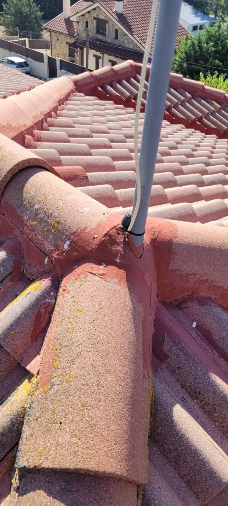 Impermeabilización de remates en tejado de Lozoyuela con sellador rojo en las uniones de tejas y tubo de antena