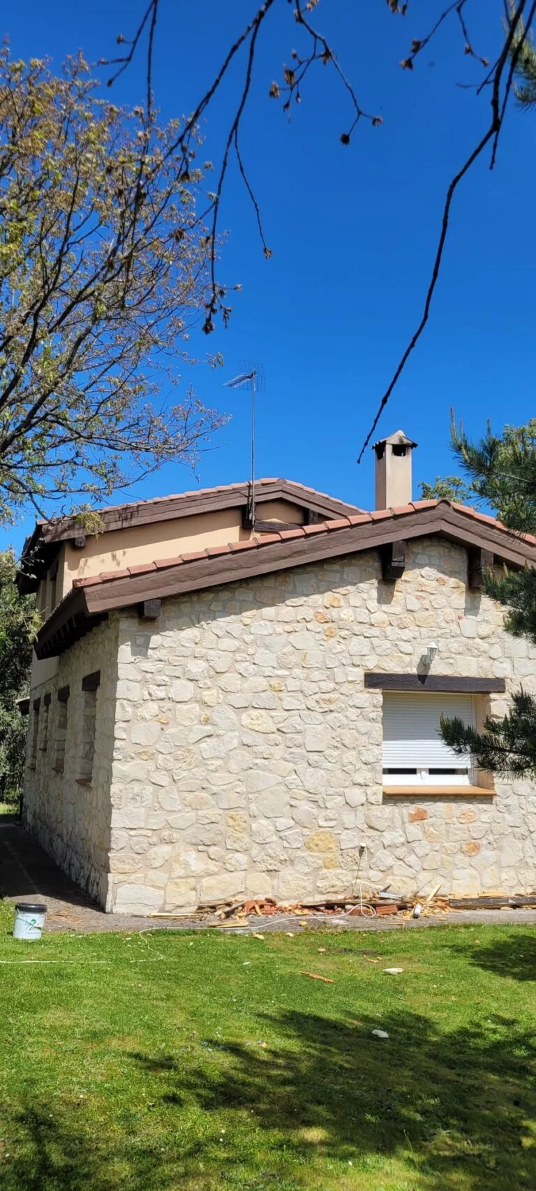Arreglo de aleros en Riaza, mostrando la reparación de la parte superior de una casa con tejas y detalles en la fachada de piedra