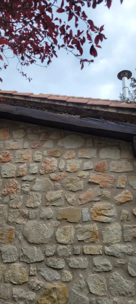 Arreglo de aleros en Riaza, mostrando reparación en el alero de tejas con detalles en la fachada de piedra.