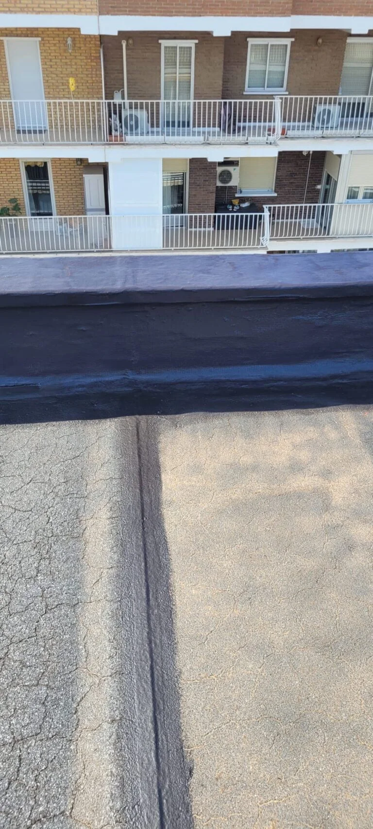 Proceso de arreglo de terraza en Alcalá de Henares con aplicación de recubrimiento negro sobre la base de la terraza.
